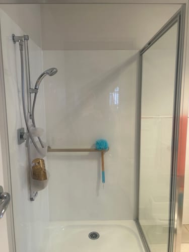 Customer's KoalaCloth XXL Bundle used to clean a white shower stall, leaving the glass and tiles spotless.